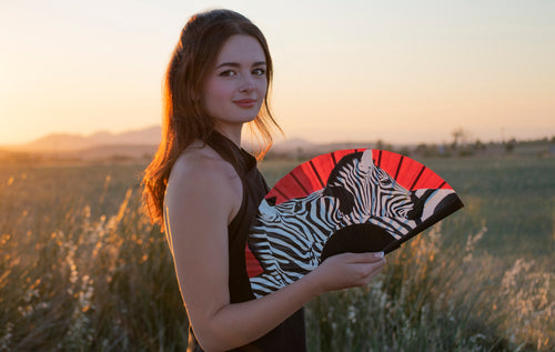 Abanico artesanal con estampado de cebras y fondo rojo